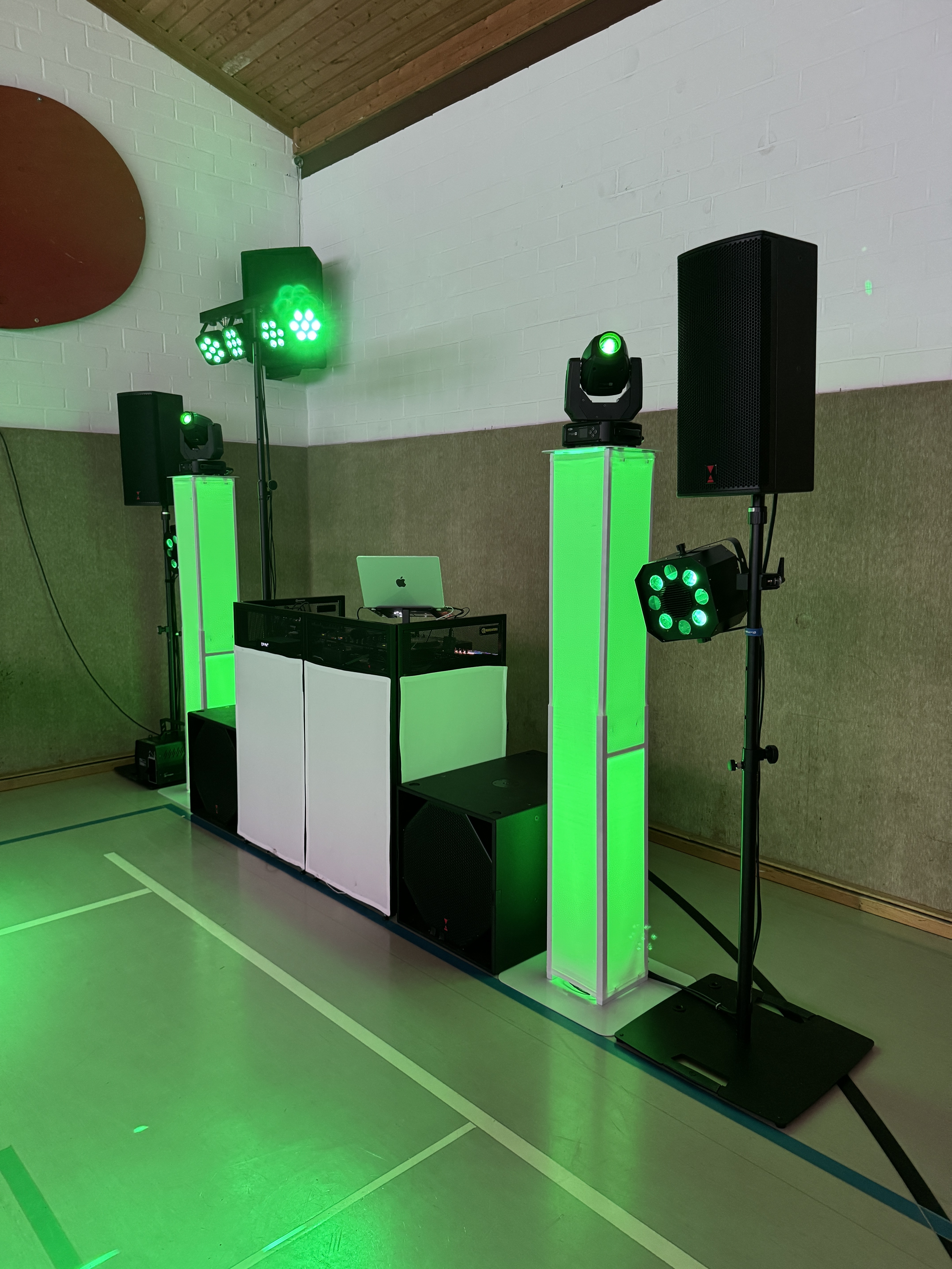 DJ-Setup mit grüner Beleuchtung in einer Sporthalle